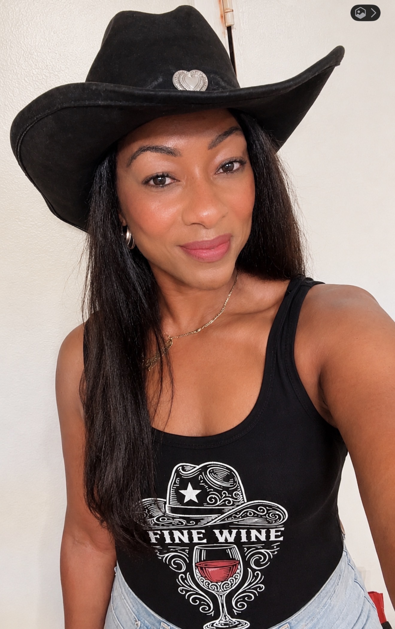 Coach Maisha wearing a black cowboy hat and Fine Wine shirt